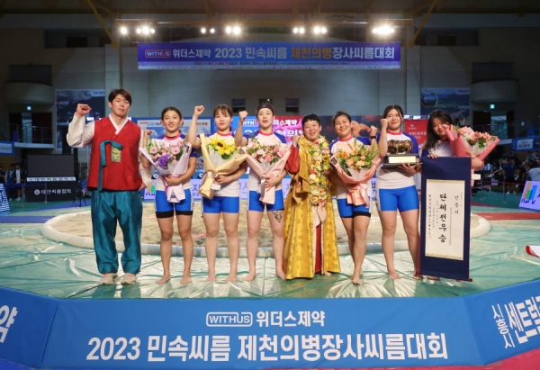 26일(수) 충청북도 제천시 제천체육관 에서 열린 '위더스제약 2023 제천의병장사씨름대회' 여자부 단체전에서 우승한 안산시청(경기도)이 김기백 감독대행(오른쪽 첫번째)과 황소트로피와 인증서를 들고 기념 촬영을 하고 있다.